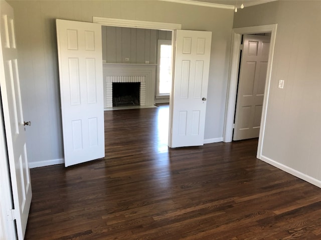 unfurnished living room featuring a fireplace, dark hardwood / wood-style flooring, and ornamental molding