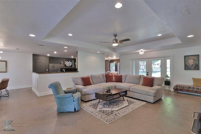 living room featuring french doors, ceiling fan, and a raised ceiling