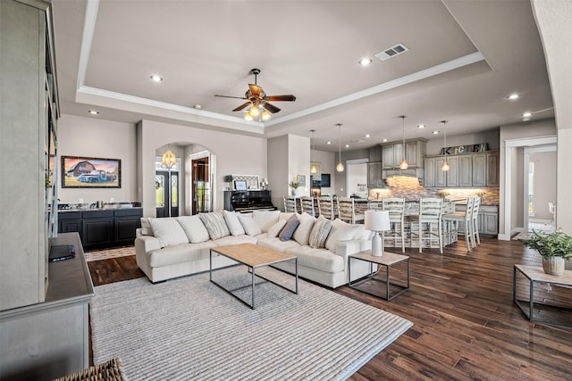 living room with crown molding, ceiling fan, dark hardwood / wood-style floors, and a raised ceiling