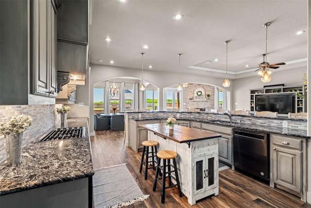 kitchen featuring sink, a center island, black dishwasher, a kitchen bar, and a raised ceiling