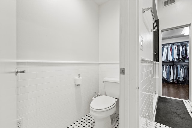 bathroom with tile patterned floors, toilet, and tile walls