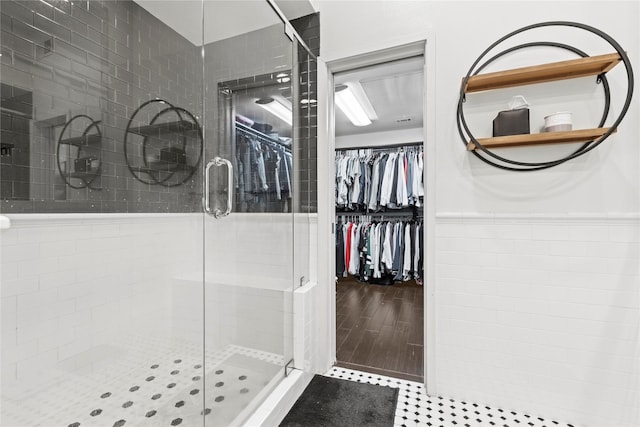 bathroom featuring hardwood / wood-style floors, an enclosed shower, and tile walls