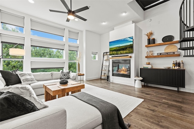 living room with ceiling fan, dark hardwood / wood-style flooring, and a high ceiling