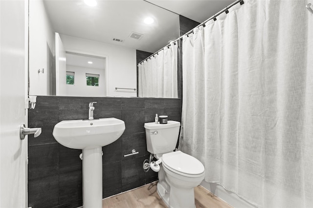 bathroom featuring toilet, a shower with shower curtain, tile walls, and hardwood / wood-style flooring