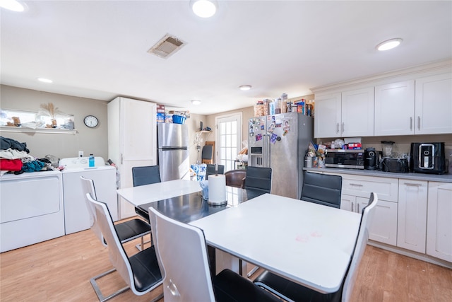 kitchen with white cabinetry, a kitchen island, washing machine and clothes dryer, light hardwood / wood-style floors, and stainless steel appliances