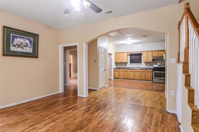 kitchen featuring sink, hardwood / wood-style flooring, stainless steel range oven, and ceiling fan