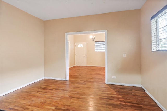 unfurnished room with an inviting chandelier and hardwood / wood-style flooring