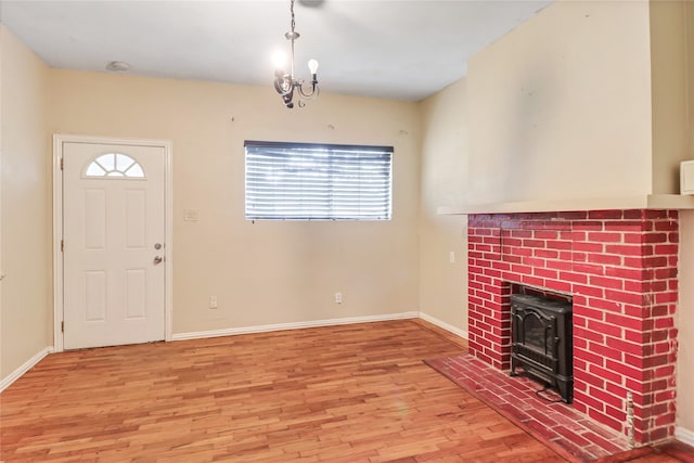 entrance foyer featuring an inviting chandelier, a brick fireplace, and light hardwood / wood-style flooring