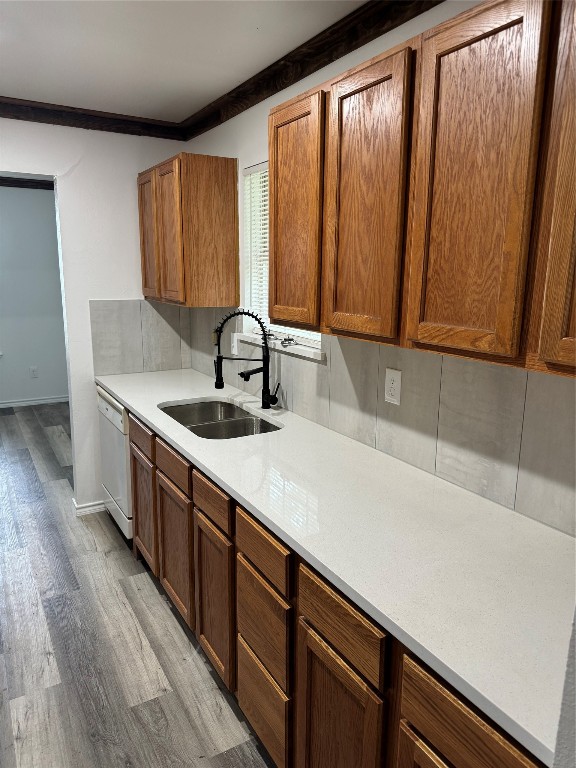 kitchen featuring sink, crown molding, light wood-type flooring, and white dishwasher