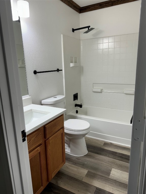 full bathroom featuring toilet, vanity with extensive cabinet space, tiled shower / bath, wood-type flooring, and ornamental molding