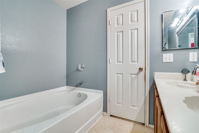 bathroom featuring tile flooring, vanity, a textured ceiling, and a tub