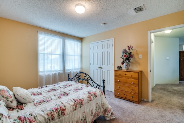 carpeted bedroom with a closet and a textured ceiling