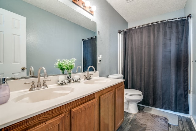 bathroom featuring toilet, dual bowl vanity, and a textured ceiling