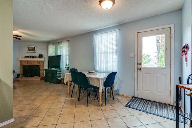 dining space featuring ceiling fan, light tile floors, and a fireplace