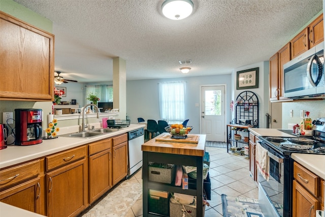 kitchen with electric range, dishwasher, sink, and light tile flooring