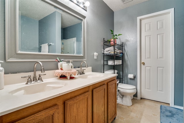 bathroom with a textured ceiling, tile floors, toilet, and dual vanity