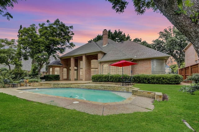 pool at dusk featuring a lawn