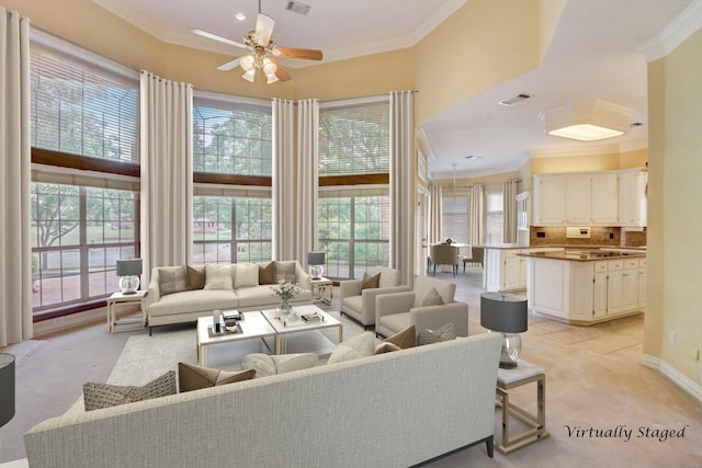 living room with a high ceiling, ceiling fan, ornamental molding, and light tile patterned flooring