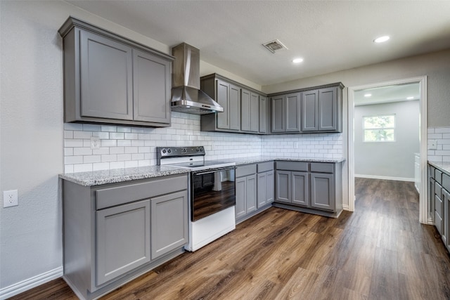 kitchen with gray cabinets, tasteful backsplash, white electric range oven, wall chimney exhaust hood, and dark hardwood / wood-style flooring