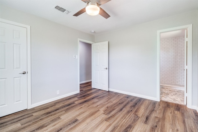 unfurnished bedroom with ceiling fan, dark hardwood / wood-style flooring, and connected bathroom