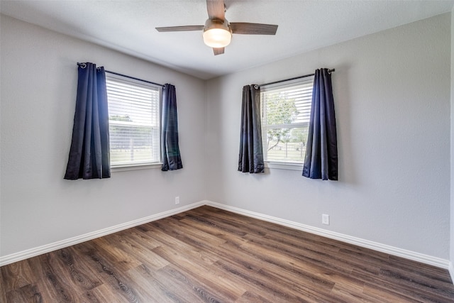 empty room featuring a healthy amount of sunlight, dark hardwood / wood-style flooring, and ceiling fan