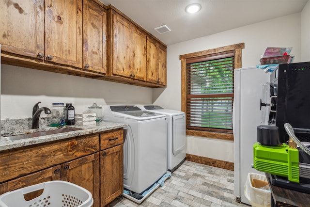 clothes washing area with washer and clothes dryer, sink, and cabinets