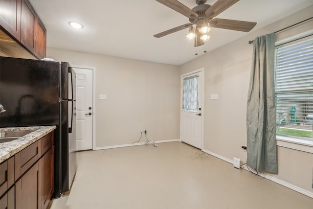 kitchen with light stone counters, ceiling fan, and sink