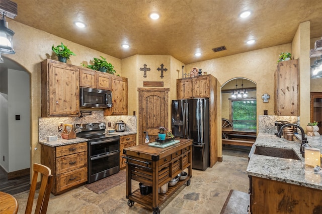 kitchen with backsplash, light stone counters, appliances with stainless steel finishes, and sink