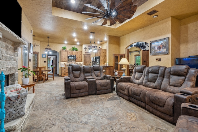 cinema room featuring a stone fireplace and ceiling fan