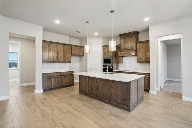 kitchen with built in microwave, sink, decorative light fixtures, black electric stovetop, and light wood-type flooring