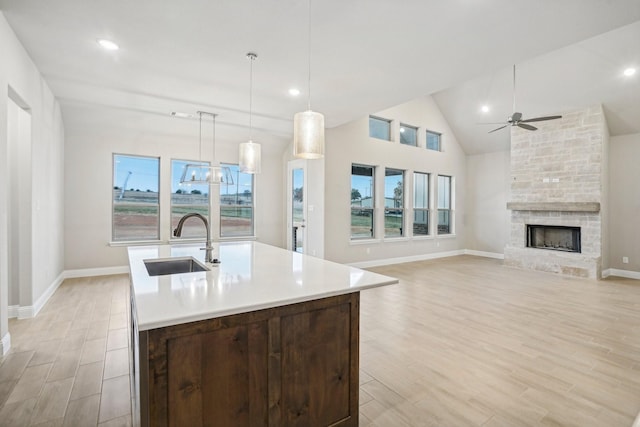 kitchen with a stone fireplace, a healthy amount of sunlight, sink, and hanging light fixtures