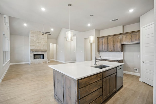 kitchen featuring stainless steel dishwasher, light wood-type flooring, sink, and a kitchen island with sink