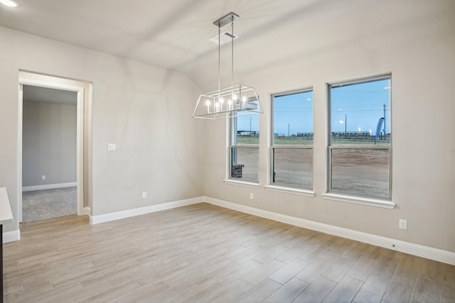 unfurnished dining area with lofted ceiling, light hardwood / wood-style flooring, and a notable chandelier