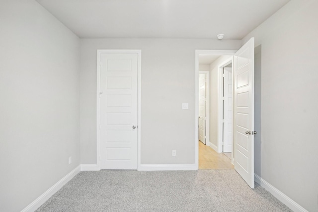 unfurnished bedroom with a closet and light colored carpet