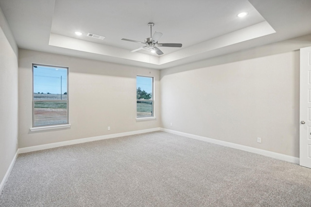 spare room featuring ceiling fan, a raised ceiling, and carpet floors