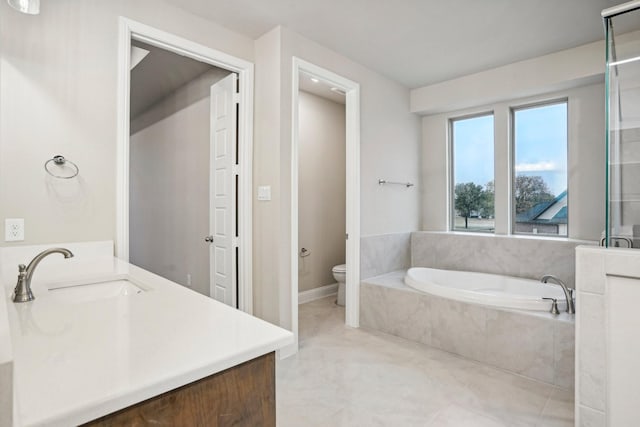 bathroom featuring tile patterned flooring, vanity, toilet, and tiled bath