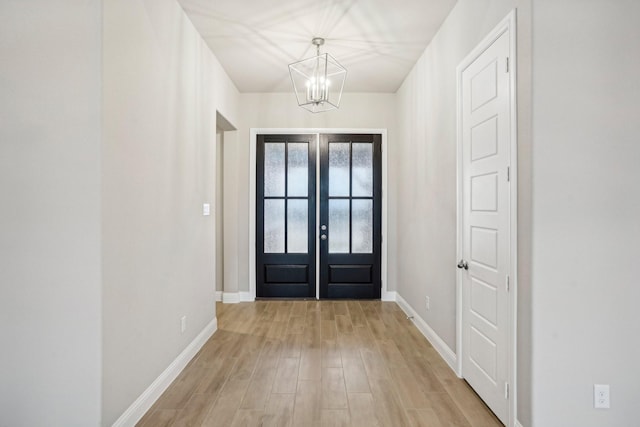 entrance foyer with french doors, an inviting chandelier, and light wood-type flooring