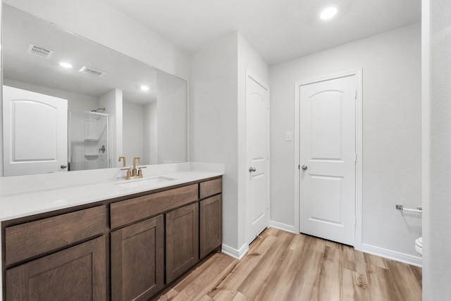 bathroom with vanity, toilet, hardwood / wood-style floors, and an enclosed shower