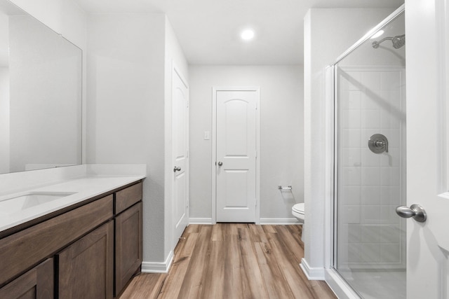 bathroom with hardwood / wood-style flooring, vanity, a shower with door, and toilet