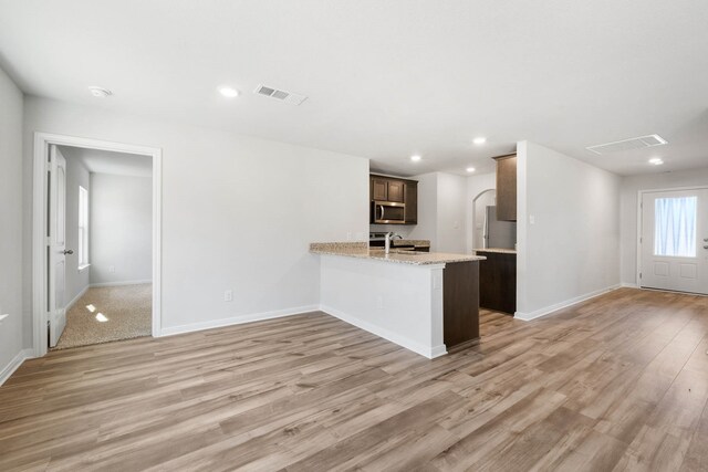 kitchen with stainless steel appliances, kitchen peninsula, light hardwood / wood-style flooring, and sink