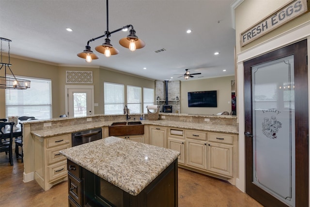 kitchen with a center island, a wood stove, hanging light fixtures, cream cabinetry, and light stone counters