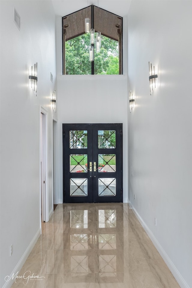 entryway featuring a towering ceiling and french doors