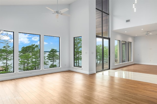 spare room with a high ceiling, ceiling fan, and a healthy amount of sunlight