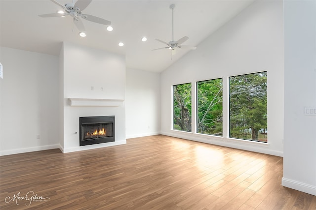 unfurnished living room with hardwood / wood-style flooring, ceiling fan, and high vaulted ceiling