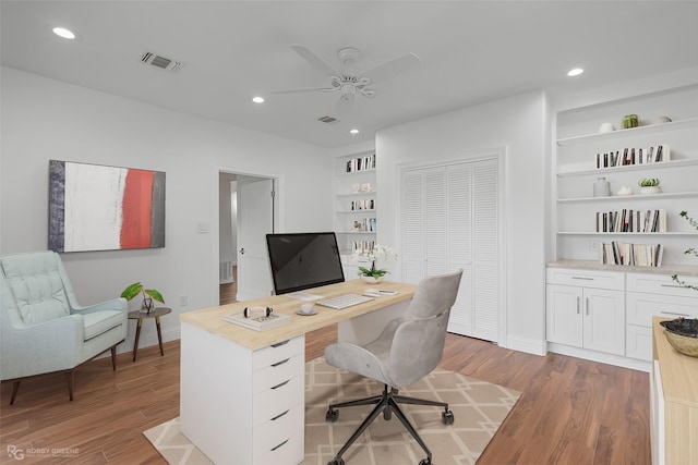 office area with built in shelves, dark hardwood / wood-style floors, and ceiling fan