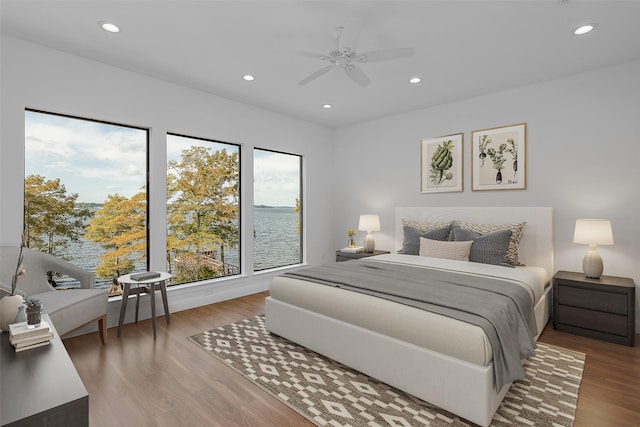 bedroom featuring ceiling fan, light hardwood / wood-style flooring, and a water view