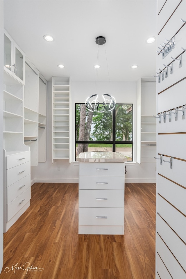 spacious closet featuring dark wood-type flooring and an inviting chandelier