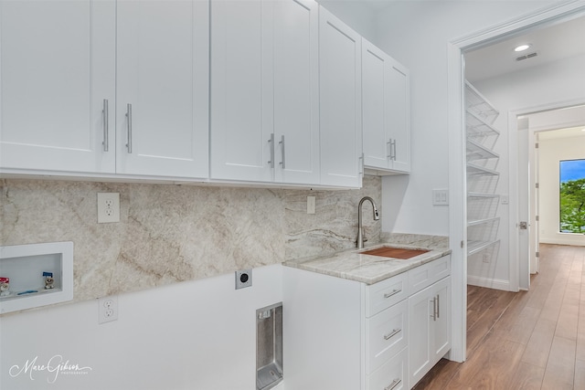 clothes washing area with sink, washer hookup, cabinets, hookup for an electric dryer, and light wood-type flooring