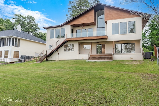 rear view of house featuring ceiling fan, cooling unit, and a lawn