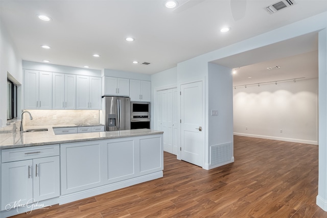 kitchen with white cabinets, sink, dark hardwood / wood-style floors, appliances with stainless steel finishes, and kitchen peninsula